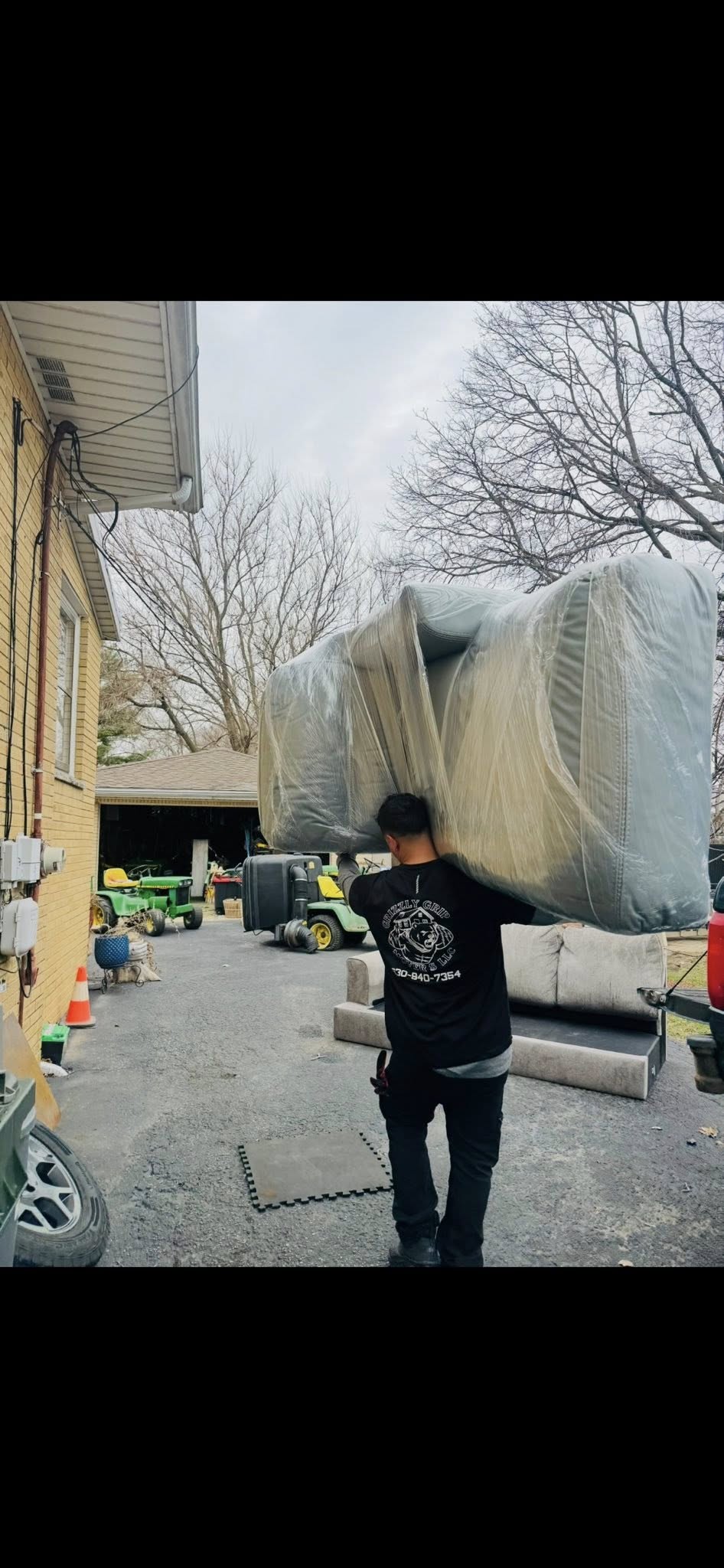 Mover carrying large wrapped sofa on his back