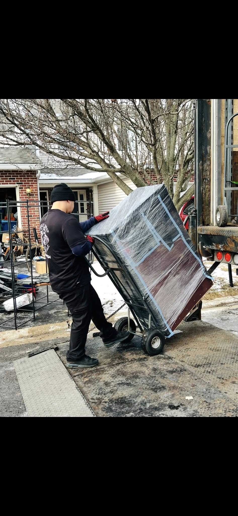Mover using dolly to transport wrapped furniture